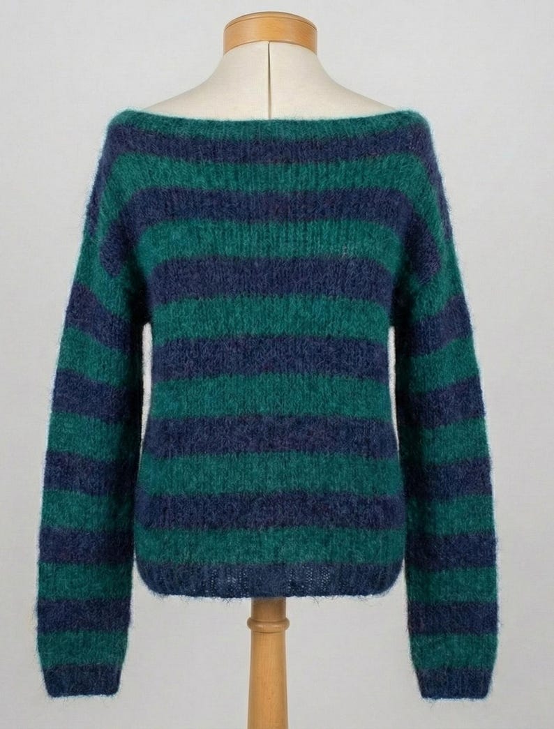 May include: A green and navy blue striped sweater with a boat neck. The long-sleeved sweater is displayed on a mannequin. The sweater's stripes are horizontal and evenly spaced, creating a classic and cozy look. The fabric appears soft and textured.
