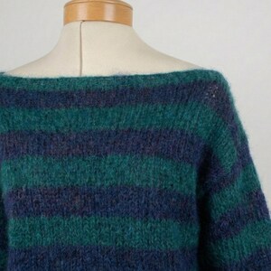 May include: A green and navy blue striped sweater with a boat neck. The sweater is made of a soft, textured material and is displayed on a mannequin. The stripes are horizontal and evenly spaced.
