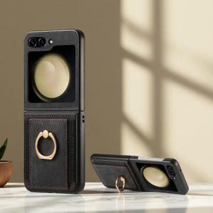 Puede incluir: Funda de teléfono negra con soporte de anillo dorado. La funda se muestra abierta y cerrada. La funda tiene una ventana rectangular para la cámara del teléfono y una textura similar al cuero con costuras marrones.