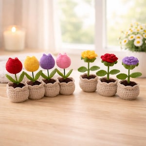 May include: A collection of handmade crochet flowers in small, beige pots. The flowers include red, yellow, purple, pink, yellow, red, and purple blooms. Each flower has green leaves and sits in a brown, soil-like material.