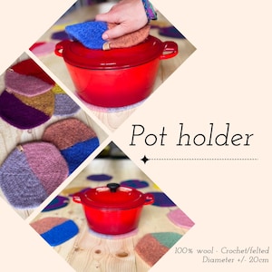 Puede incluir: Una olla de hierro fundido esmaltado roja con tapa negra descansa sobre un salvamanteles de lana afieltrada. Los salvamanteles son de dos tonos en varios colores, incluyendo azul, rosa y marrón. Se muestra el texto "Pot holder".