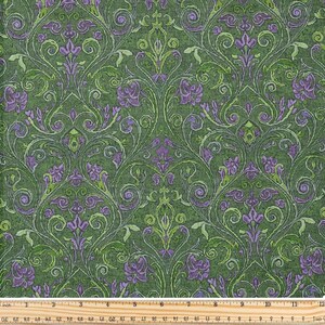 Könnte beinhalten: Grüner Stoff mit einem sich wiederholenden floralen Damastmuster in Grün- und Lilatönen. Das Design umfasst stilisierte Blumen, Schriftrollen und Blätter. Ein Lineal mit Zoll- und cm-Maßen befindet sich unten.