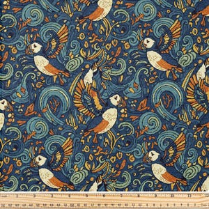 May include: A patterned fabric featuring puffin birds, waves, and foliage in blue, orange, and cream. The design includes a ruler with cm measurements along the bottom. The fabric is approximately 76 cm wide.