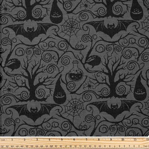 May include: A grey fabric featuring a repeating black Halloween pattern. The design includes bats, trees, spiderwebs, potion bottles, and teardrop-shaped figures with jack-o'-lantern faces. The fabric is measured with a ruler in inches and centimetres.