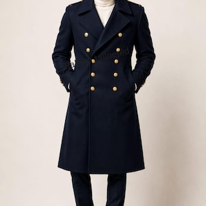 May include: A navy blue double-breasted wool coat featuring gold-toned buttons, wide lapels, and shoulder epaulets. The coat is worn over a cream-colored turtleneck sweater and dark trousers, paired with black leather dress shoes.