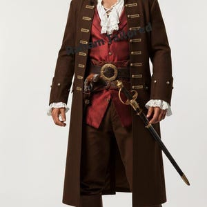 Può includere: Un costume da pirata composto da un lungo cappotto marrone con bottoni dorati, un gilet rosso, una camicia bianca con volant, pantaloni marroni e stivali marroni. Include un tricorno nero con bandana rossa, una cintura e una spada nel fodero.