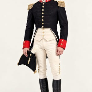 Könnte beinhalten: Eine schwarze Militärjacke mit goldenen Knöpfen, roten Manschetten und goldenen Epauletten, kombiniert mit einer cremefarbenen Weste und Hose, schwarzen kniehohen Stiefeln und einem schwarzen Zweispitz mit weißer Feder. Text Raham tailoered.