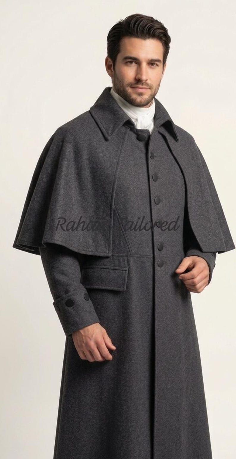 May include: A charcoal gray wool coat with a cape-like shoulder design. The coat features a notched collar, button closures, and a single pocket. The sleeves have buttoned cuffs. The text "Raha Tailored" is visible on the cape.