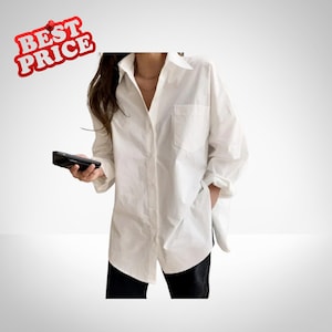 以下が含まれることがあります： 黒い持ち手と「But First, Coffee」のテキストが黒い太字で書かれた白いセラミックマグ。マグカップはぼやけた背景に置かれており、居心地の良い環境を示唆しています。