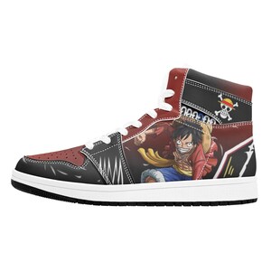 Puede incluir: Zapatilla alta en rojo, negro y blanco. El diseño presenta un personaje de dibujos animados y un emblema de calavera y huesos cruzados. La zapatilla tiene suela y cordones blancos. La zapatilla mide unos 25 cm de largo.