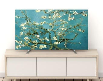 May include: A flat-screen television displays a painting of a blossoming tree against a teal background. The artwork features white flowers and brown branches. The TV is on a light wood-tone cabinet with white doors.