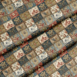 May include: Close-up of a fabric with a patchwork design. The squares feature floral and ornamental patterns in shades of blue, red, beige, and green. The fabric has a textured appearance and a vintage aesthetic.