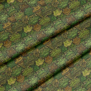 Può includere: Un tessuto con un motivo ripetuto di illustrazioni dettagliate di rane in tonalità di verde, marrone e beige. Le rane hanno grandi occhi e disegni intricati, creando una superficie strutturata e visivamente ricca.