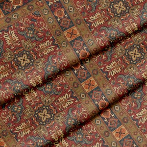 Puede incluir: Primer plano de una tela estampada con un diseño de alfombra tradicional. La tela presenta una rica paleta de colores rojo, azul, dorado y naranja. El diseño incluye formas geométricas y motivos florales.