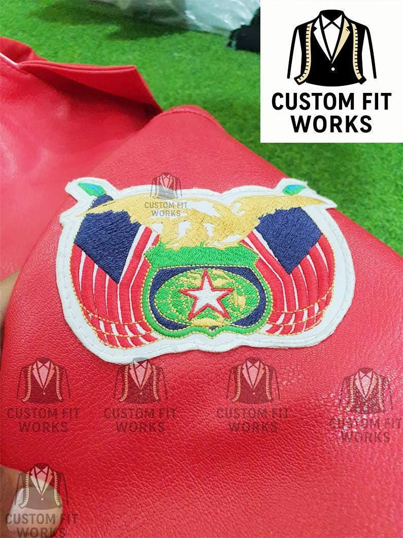 May include: Close-up of a red leather item with an embroidered patch featuring a star, eagle, and flag design. The patch is surrounded by a white border. The text "CUSTOM FIT WORKS" is visible.