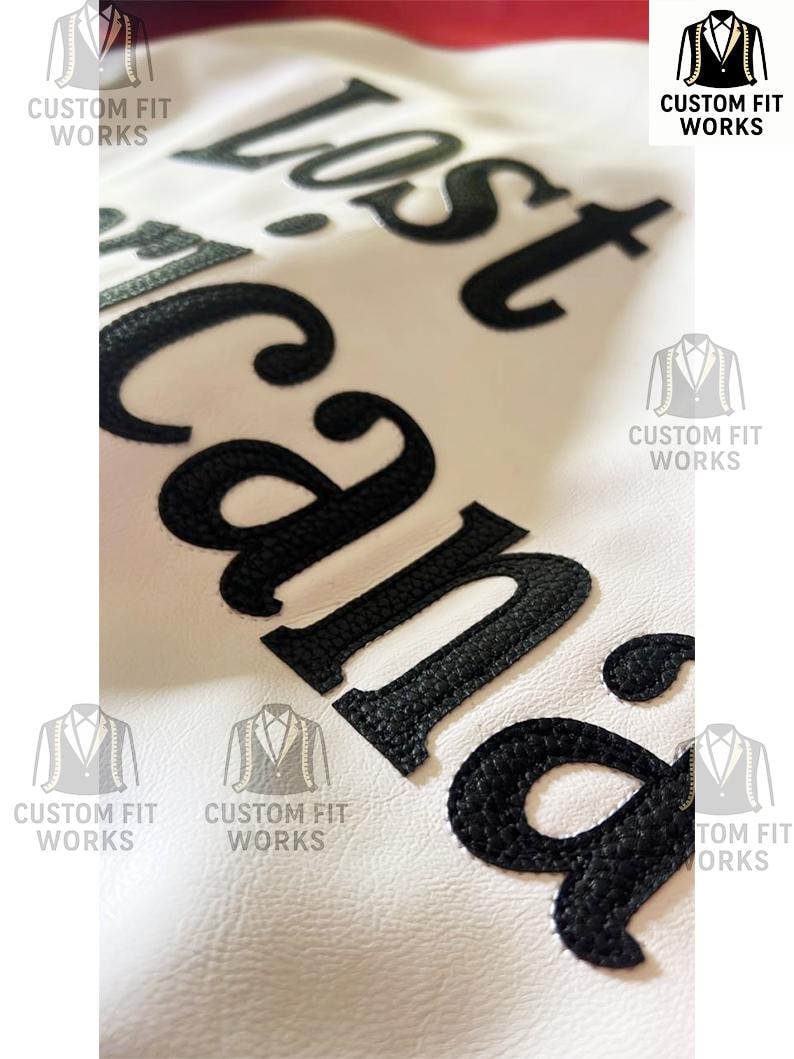 May include: Close-up of a white leather jacket with the words "Lost Cana" embroidered in black. The jacket features the "Custom Fit Works" logo in multiple locations.