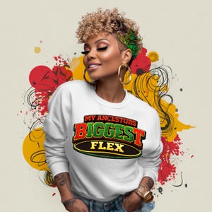 May include: White sweatshirt with the text "MY ANCESTORS BIGGEST FLEX" in red, green, and black. The sweatshirt has long sleeves and a crew neck. The background features abstract red, yellow, and black shapes.