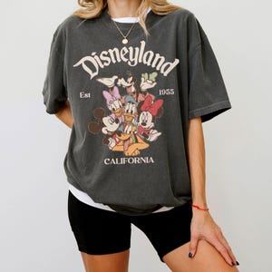 Op de afbeelding: Een witte keramische mok met een zwart handvat en de tekst "But First, Coffee" in een zwarte, handgeschreven lettertype. De mok staat op een wit oppervlak.