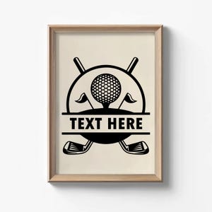 May include: Framed print featuring a black and white golf-themed design. The artwork includes a golf ball on a tee, crossed golf clubs, and the text "TEXT HERE" in a rectangular banner. Two small flags flank the golf ball.