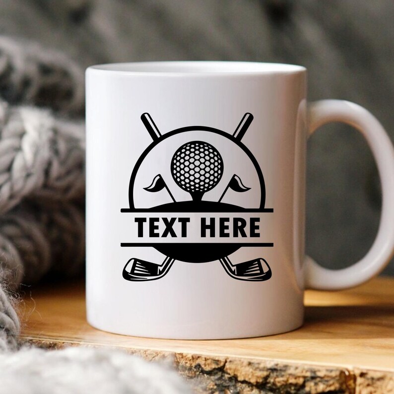 May include: White ceramic mug featuring a black golf-themed design. The design includes a golf ball, flags, golf clubs, and the text "TEXT HERE" in a bold font. The mug has a curved handle.