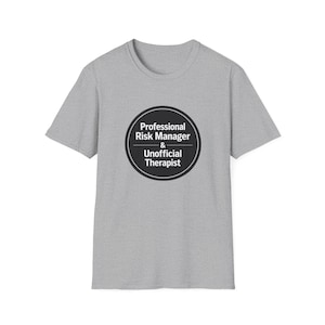Puede incluir: Una camiseta gris jaspeado con un diseño circular negro. El diseño dice "Professional Risk Manager & Unofficial Therapist" en texto blanco. La camiseta tiene mangas cortas y cuello redondo.