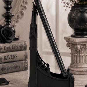 Black Gothic Cathedral phone stand displayed on a modern desk holding a smartphone.
Side view of Gothic Cathedral phone holder showing detailed medieval window design.
Front view of cathedral-inspired smartphone stand with gothic architectural details.