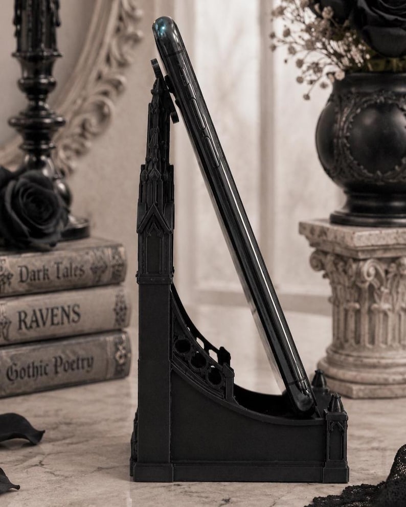 Black Gothic Cathedral phone stand displayed on a modern desk holding a smartphone.
Side view of Gothic Cathedral phone holder showing detailed medieval window design.
Front view of cathedral-inspired smartphone stand with gothic architectural details.