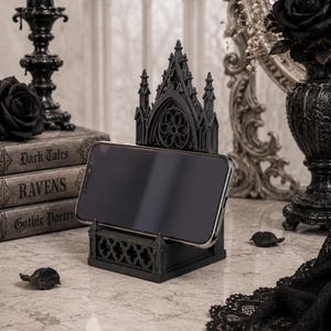 Black Gothic Cathedral phone stand displayed on a modern desk holding a smartphone.
Side view of Gothic Cathedral phone holder showing detailed medieval window design.
Front view of cathedral-inspired smartphone stand with gothic architectural details.
