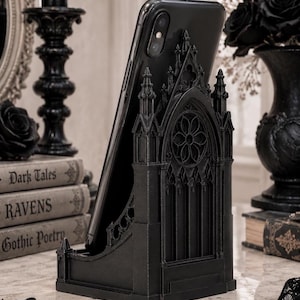 Black Gothic Cathedral phone stand displayed on a modern desk holding a smartphone.
Side view of Gothic Cathedral phone holder showing detailed medieval window design.
Front view of cathedral-inspired smartphone stand with gothic architectural details.