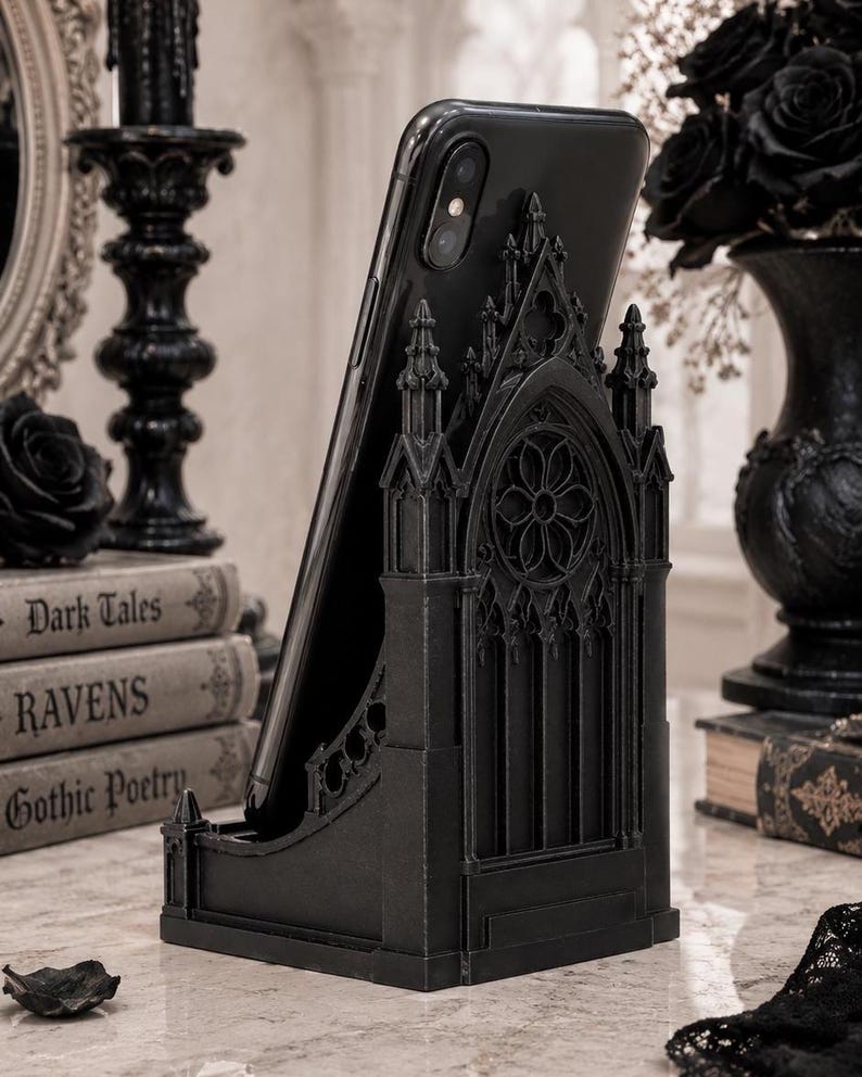 Black Gothic Cathedral phone stand displayed on a modern desk holding a smartphone.
Side view of Gothic Cathedral phone holder showing detailed medieval window design.
Front view of cathedral-inspired smartphone stand with gothic architectural details.