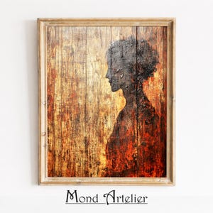 May include: A framed artwork depicting a person's profile in silhouette against a textured wooden backdrop. The piece uses warm tones of brown, orange, and red. The frame is a light wood colour. The text "Mond Artelier" is visible at the bottom of the artwork.