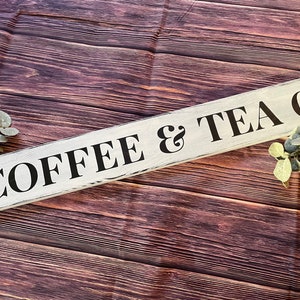 May include: White wooden sign with black lettering that reads "COFFEE & TEA CO."