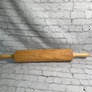 May include: A wooden rolling pin with light brown handles and a cylindrical body. The rolling pin is made of light-colored wood and is designed for baking and pastry preparation.
