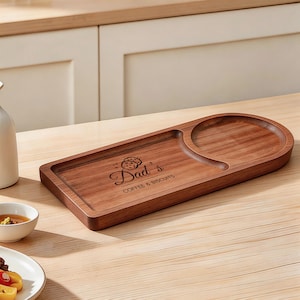 May include: A wooden serving tray with a circular recess for a mug and a rectangular section for biscuits. The tray is engraved with the words "Dad's Coffee & Biscuits".