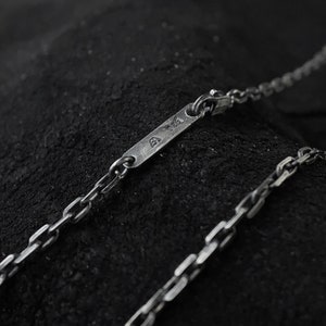 May include: A silver chain necklace with a small rectangular tag that says "925" on it.