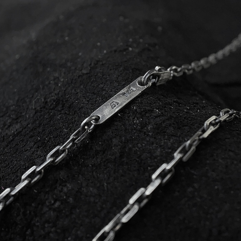 May include: A silver chain necklace with a small rectangular tag that says "925" on it.
