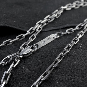 Op de afbeelding: Een zilveren ketting met een sluiting en een label met de tekst "925".