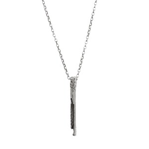 Puede incluir: Un collar de plata con un colgante largo, delgado y texturizado. El colgante es de forma rectangular simple con un borde ligeramente irregular.