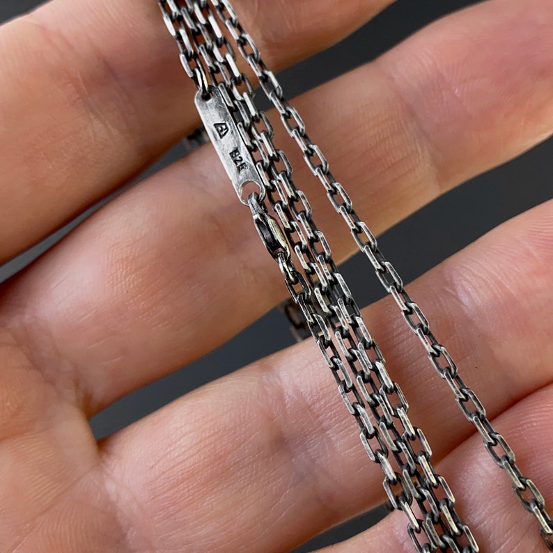 May include: A silver chain necklace with multiple strands. The chain is made of small, linked rectangles. The tag on the chain reads "A 925".