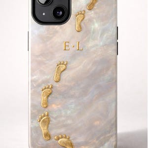 Op de afbeelding: Smartphonehoesje met een parelmoer achtergrond en een spoor van goudkleurige voetafdrukken. De initialen "E • L" zijn in goud. De hoes heeft een zwart cameramodule.
