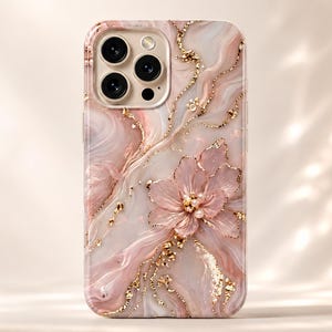 Può includere: Una custodia per telefono con un design marmorizzato nei toni del rosa, bianco e oro. La custodia presenta un motivo floreale in rilievo con dettagli dorati e un centro perlato. La custodia del telefono ha una finitura lucida.