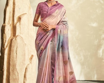 May include: A saree featuring a gradient of soft pink, lavender, and blue tones with metallic gold leaf motifs. The garment is paired with a matching short-sleeved blouse that has a collared neckline and a subtle textured pattern throughout.