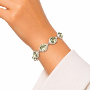 May include: A silver bracelet featuring five oval-shaped, light green gemstones. Each gemstone is set in a textured silver frame with a rope-like border, connected by small silver links to form a continuous chain around the wrist.