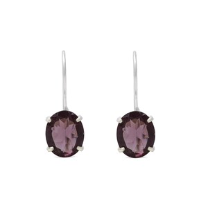 May include: A pair of drop earrings featuring oval-shaped, deep purple faceted gemstones set in silver-toned metal prongs. Each earring is suspended from a simple, curved silver-toned hook wire, showcasing a clear, polished finish on the stones.