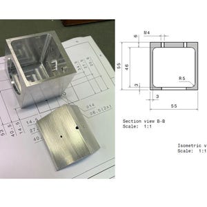 May include: A machined silver metal cube component with a hollow interior and a separate curved metal plate, displayed alongside technical engineering drawings showing dimensions like 55 mm, M4, and R5, including a section view and isometric view.