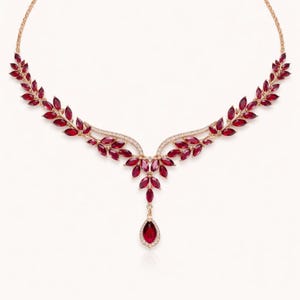 May include: A gold-coloured necklace with a leaf-inspired design, adorned with vivid red gemstones. The necklace includes a fine chain and a central pendant with a teardrop-shaped red stone, suitable for formal events.
