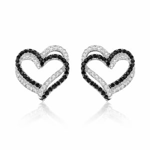 May include: A pair of heart-shaped stud earrings. Each earring features a double-layered design, with one layer of black stones and another of white stones. The earrings are set against a white background.