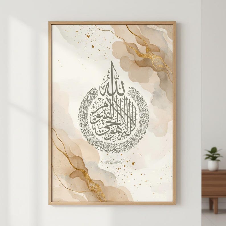 May include: A framed piece of art with Arabic calligraphy in a circular design. The calligraphy is dark grey, set against a watercolour background of beige and gold tones. The artwork is in a light brown wooden frame.