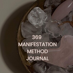 Puede incluir: Un cuenco marrón oscuro lleno de piedras transparentes e irregulares que parecen hielo y una piedra lisa de color rosa pálido en forma de corazón. El texto 369 MANIFESTATION METHOD JOURNAL está centrado en blanco sobre las piedras, con un logo.
