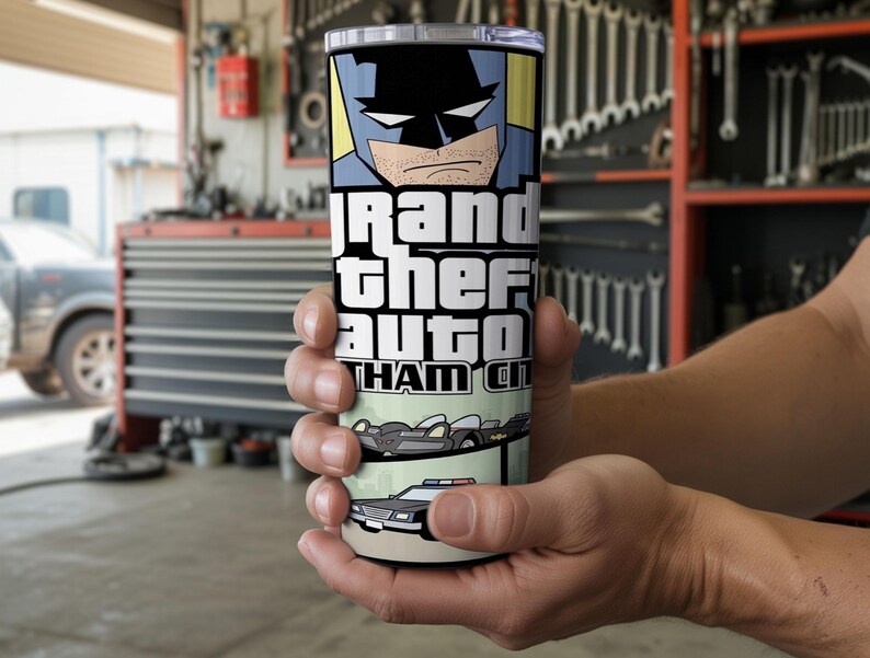 May include: A cylindrical stainless steel tumbler featuring a graphic print of a comic book style character with a mask, the text Grand Theft Auto Gotham City, a black vehicle with fins, and a police car with blue and red lights on the roof.